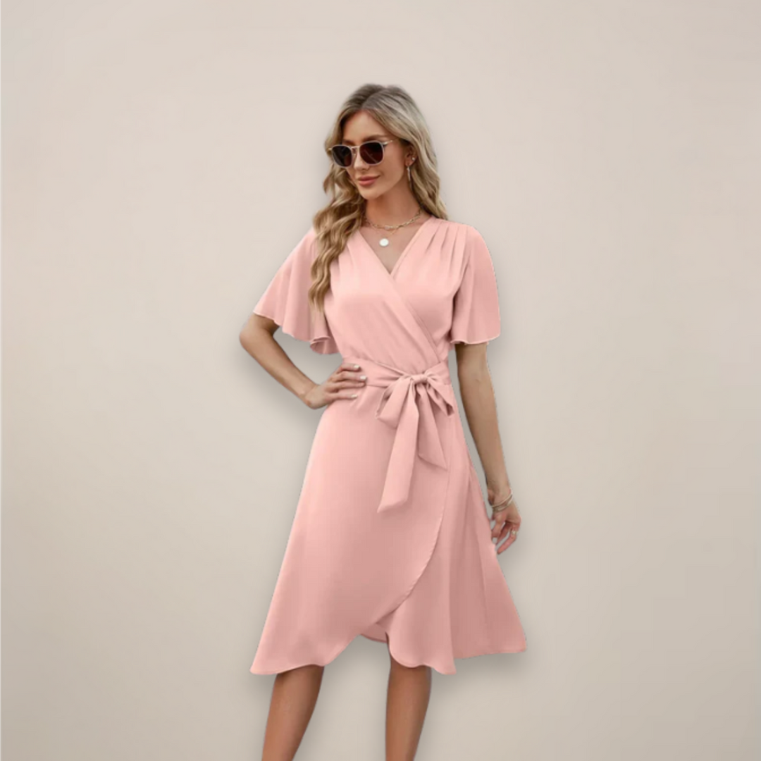 Woman showcasing a flowing midi dress with wrap styling and adjustable waist tie on a plain background.