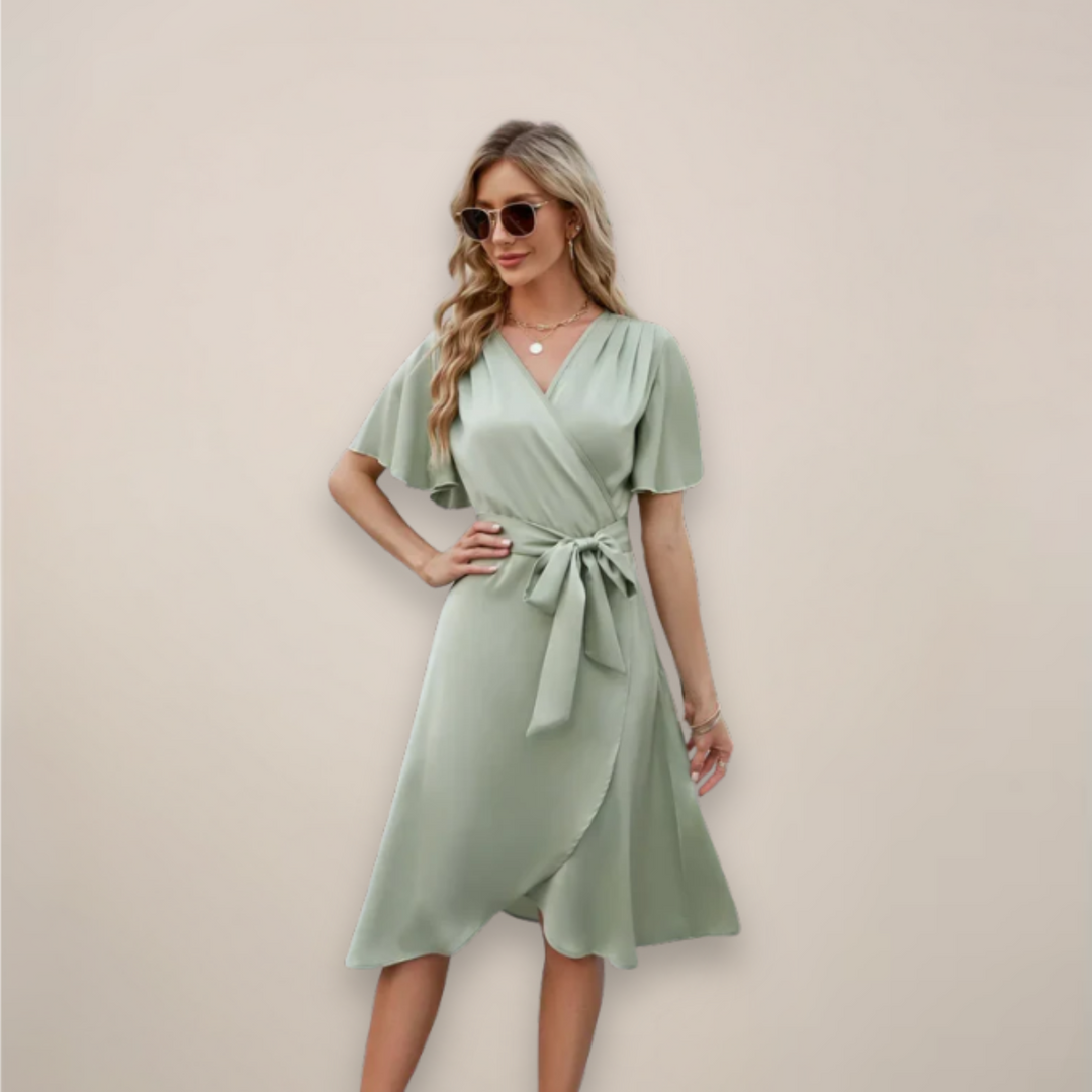 Woman in a wrap-style midi dress featuring short sleeves and a tie detail on a plain background.