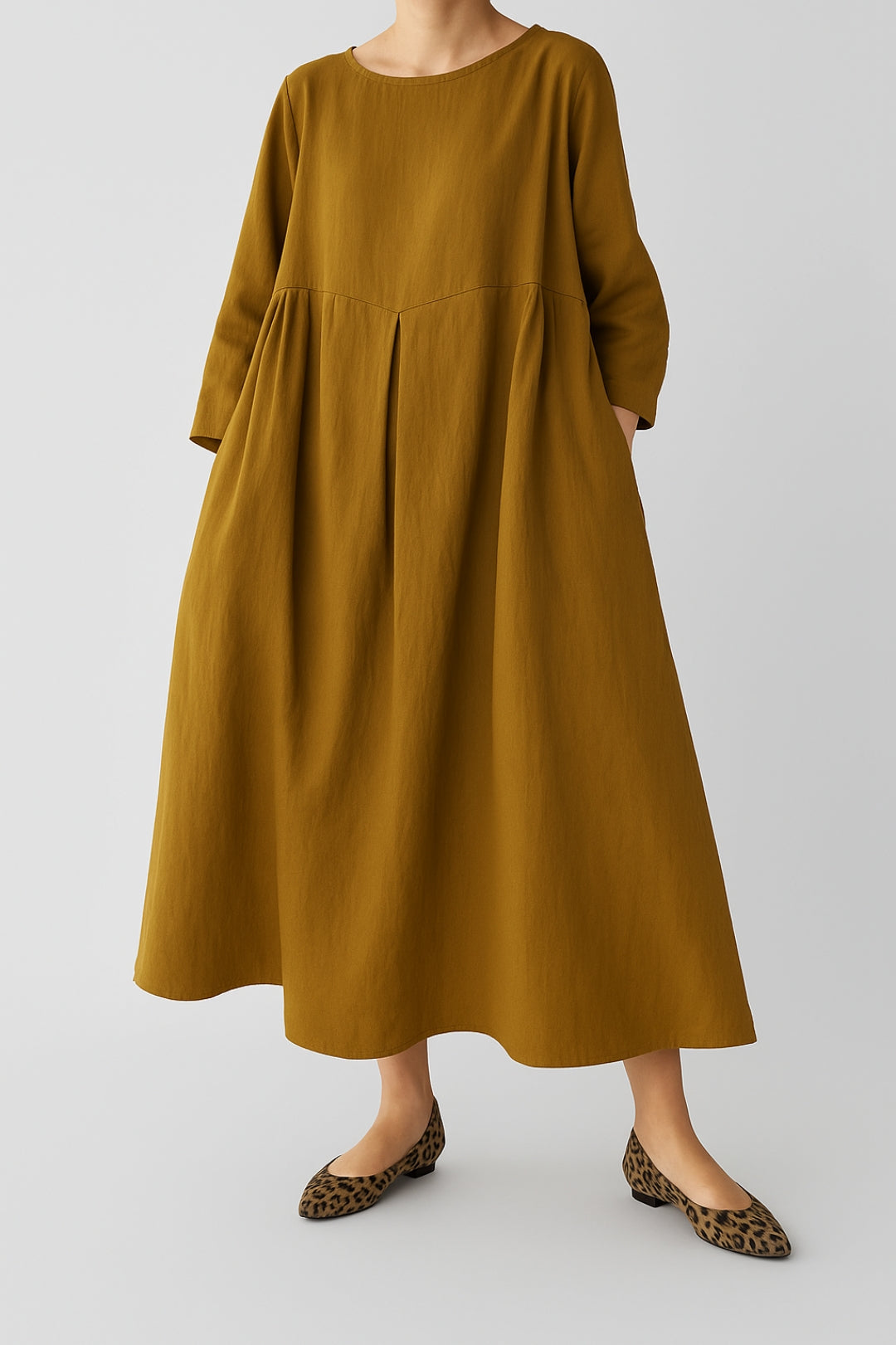 Female model in a flowing midi dress with three-quarter sleeves on a plain background.