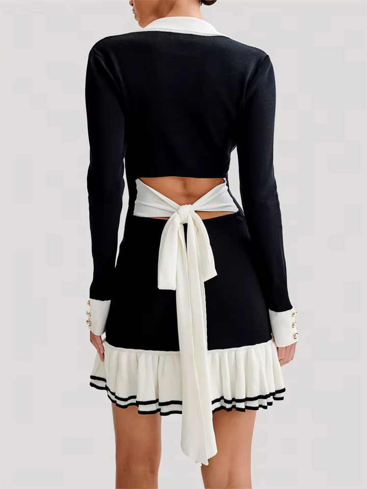 Woman modeling a long sleeve knit dress with button detail and contrast edging on a plain background.