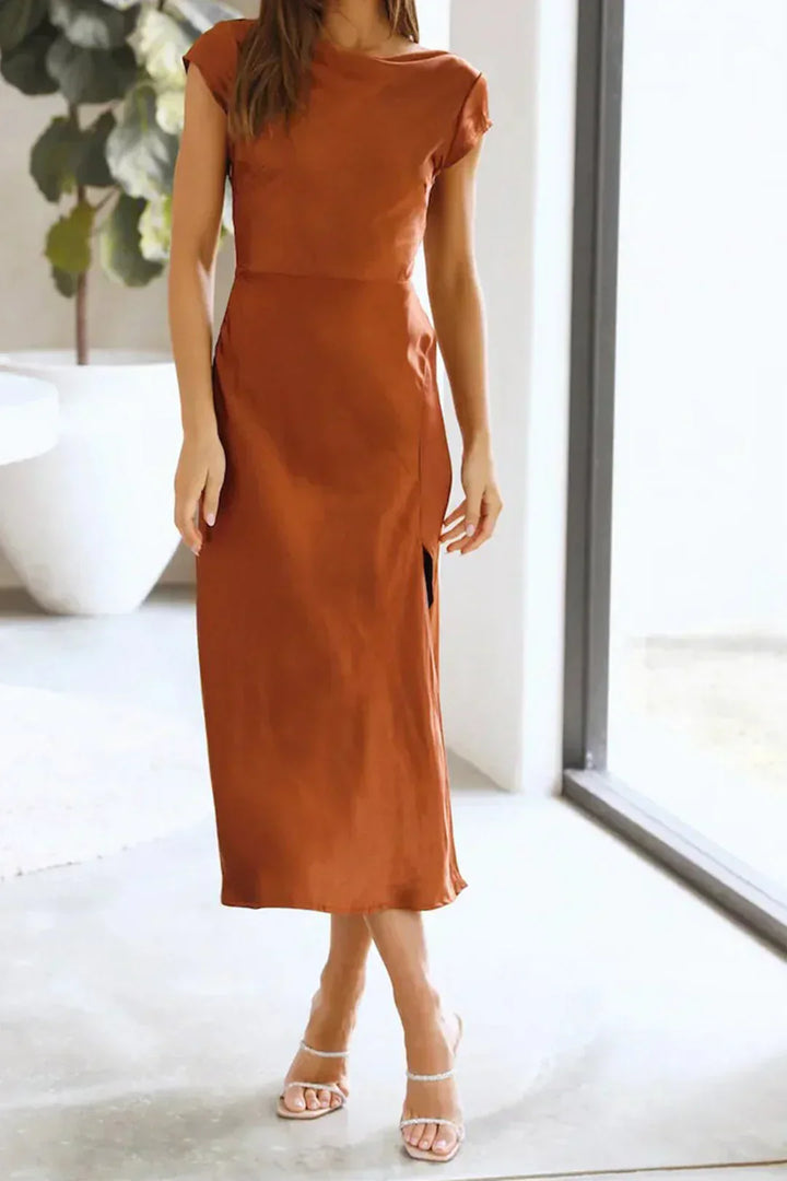 Woman styled in a draped midi dress with three-quarter sleeves and sleek fitted skirt against a plain background.