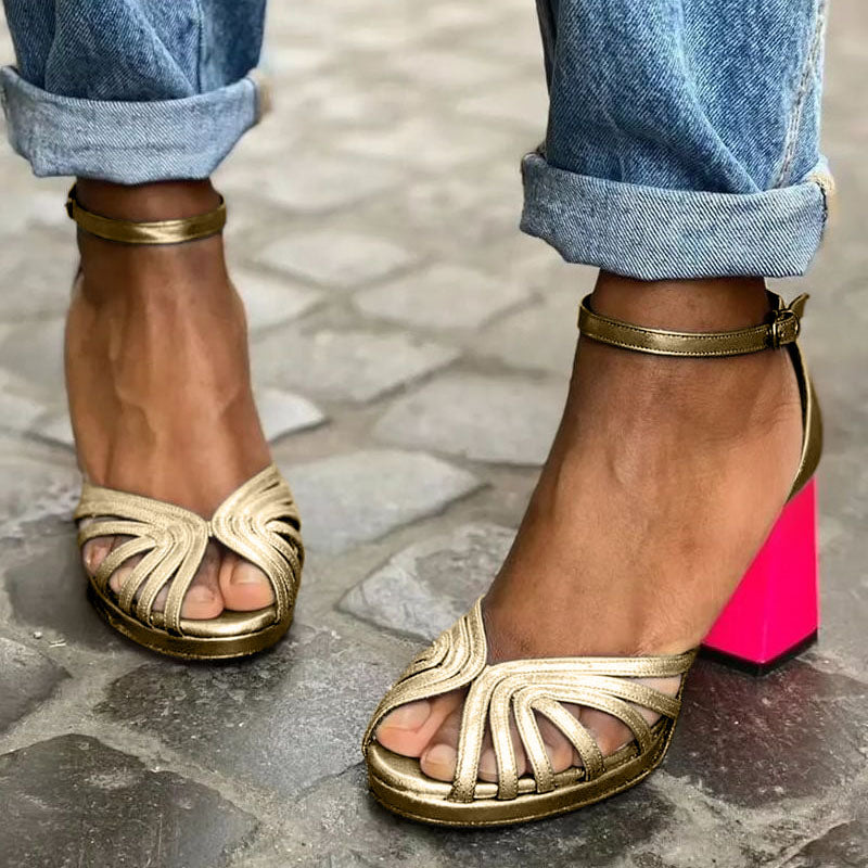 Foot wearing an elegant open-toe block heel sandal on a plain background.