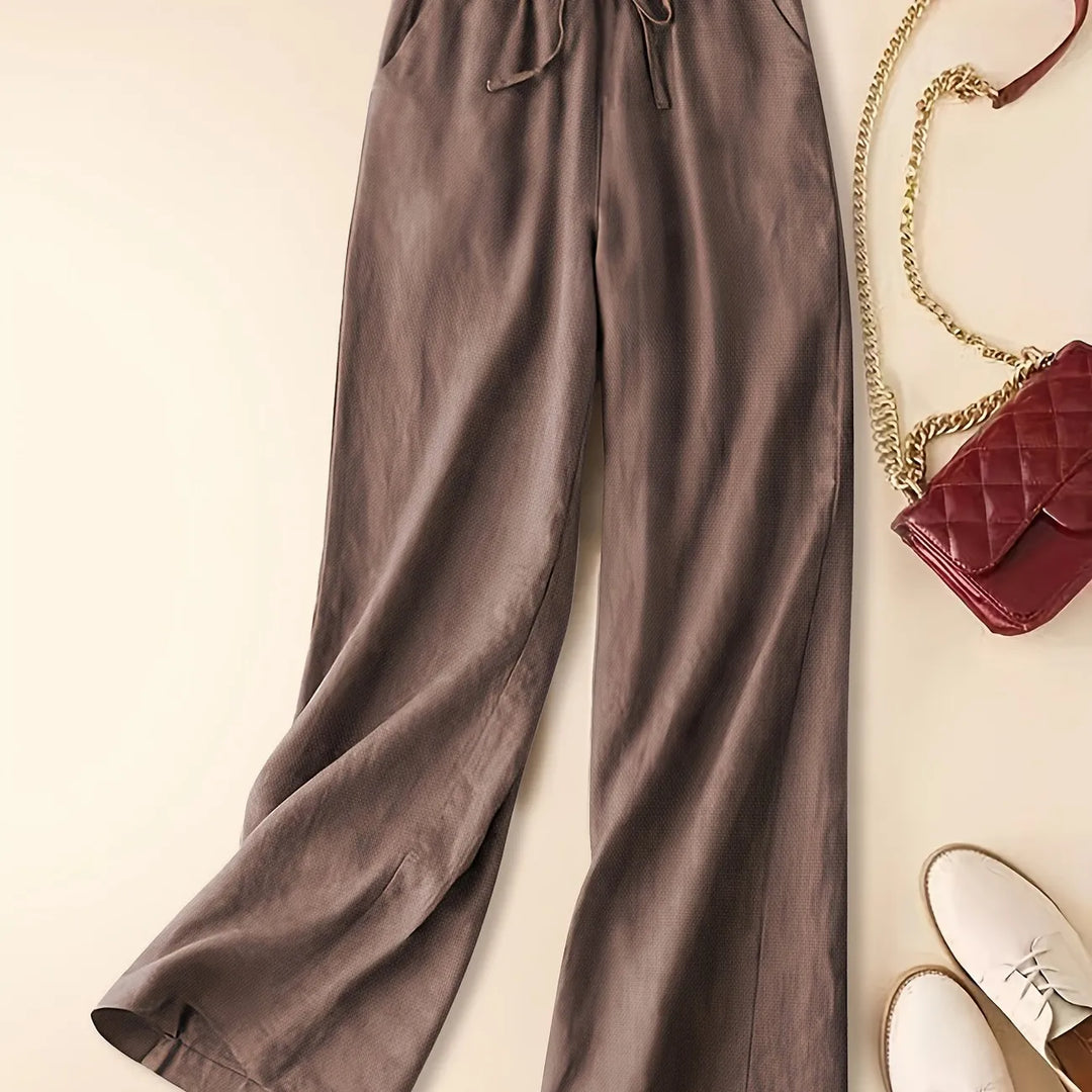 Women’s relaxed drawstring pants on a plain background with a soft draped silhouette.