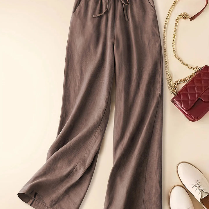 Women’s relaxed drawstring pants on a plain background with a soft draped silhouette.