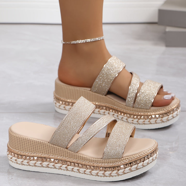 Female feet shown in glitter champagne sandals on a clean background.