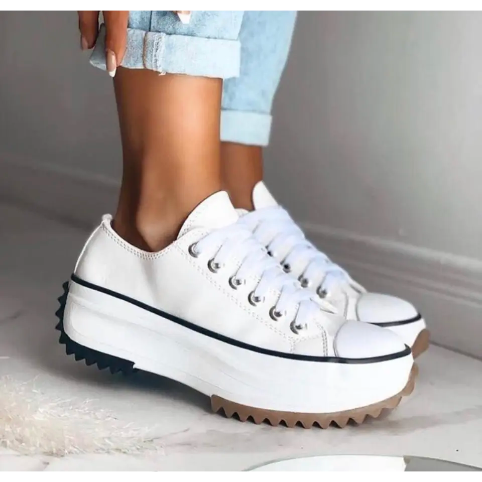 Woman modeling supportive lace-up sneakers on a plain background.