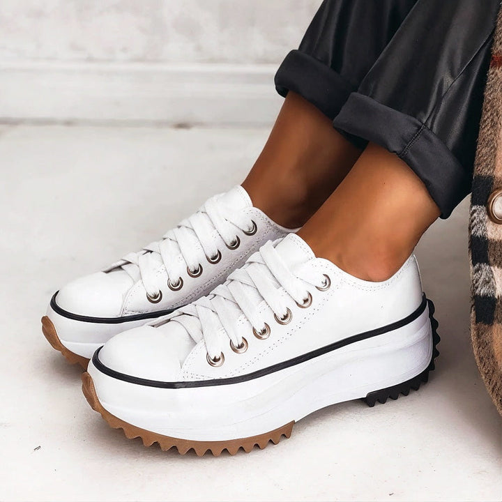 Casual women’s sneakers shown on female feet with a clean plain background.