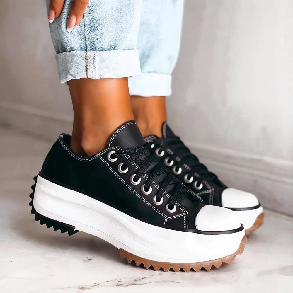 Female model showing feet wearing casual women’s sneakers on a plain background.