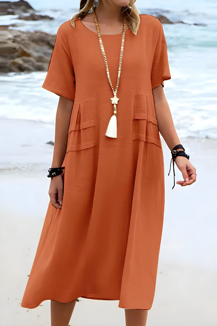  Woman showcasing a relaxed midi dress with a loose silhouette on a plain background.