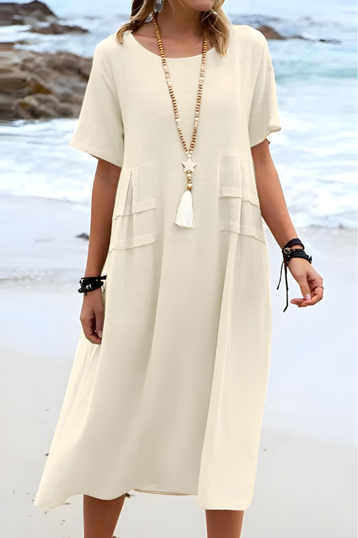 Female wearing a flowy midi dress with short sleeves against a plain background.