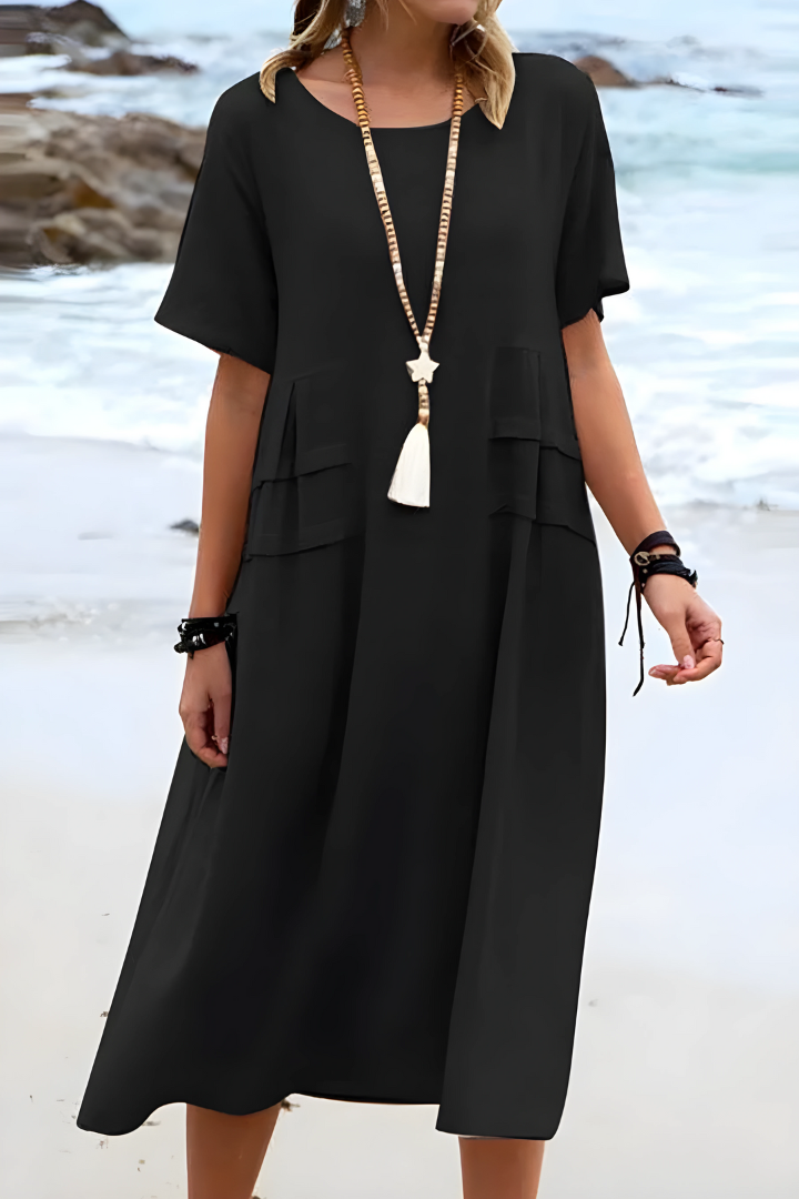  Female model in a casual midi dress featuring a flowing shape and short sleeves on a plain background.