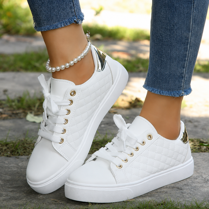 Woman modeling cushioned daily shoes against a plain neutral backdrop.