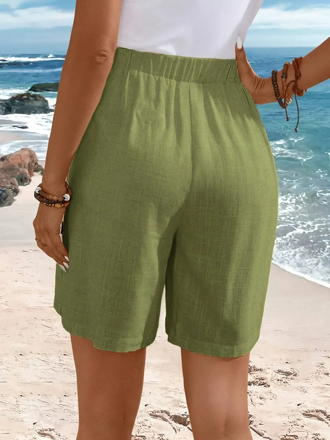 Female model wearing relaxed high-rise shorts with refined button styling.