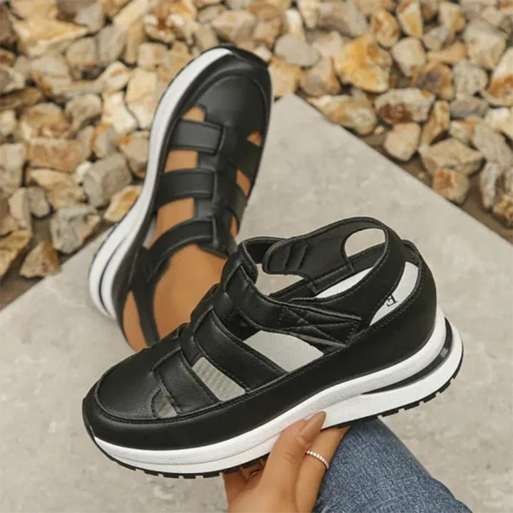Female model wearing casual elevated sneakers on a clean plain background.