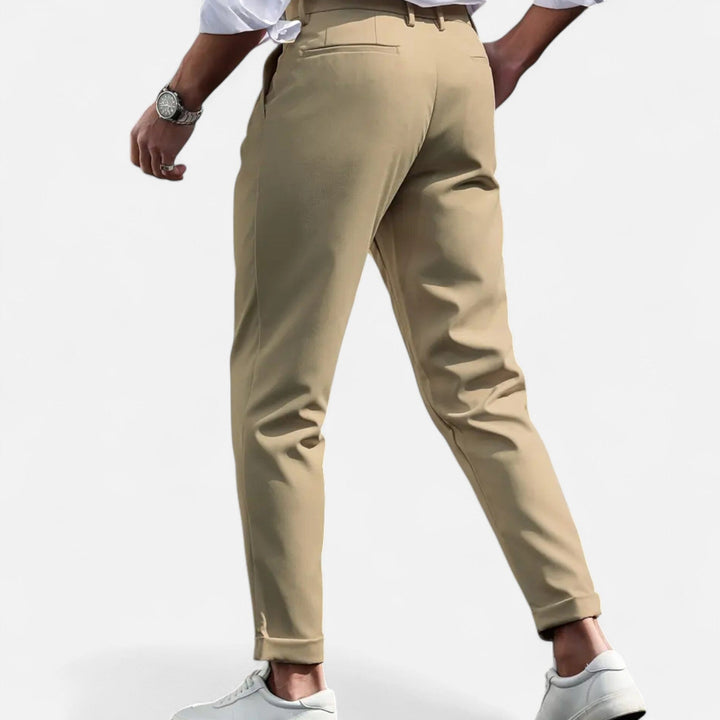  Female model presenting refined pleated pants with a tailored look on a plain background.