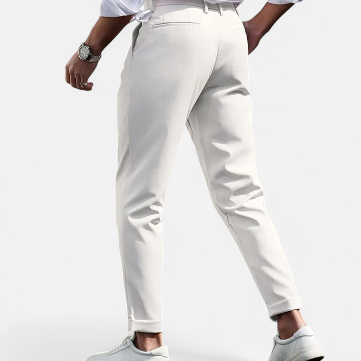Model styled in versatile pleated trousers suitable for smart casual outfits on a plain background.