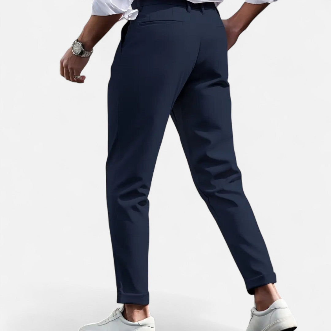 
Woman wearing tailored formal trousers with a clean finish on a plain background.