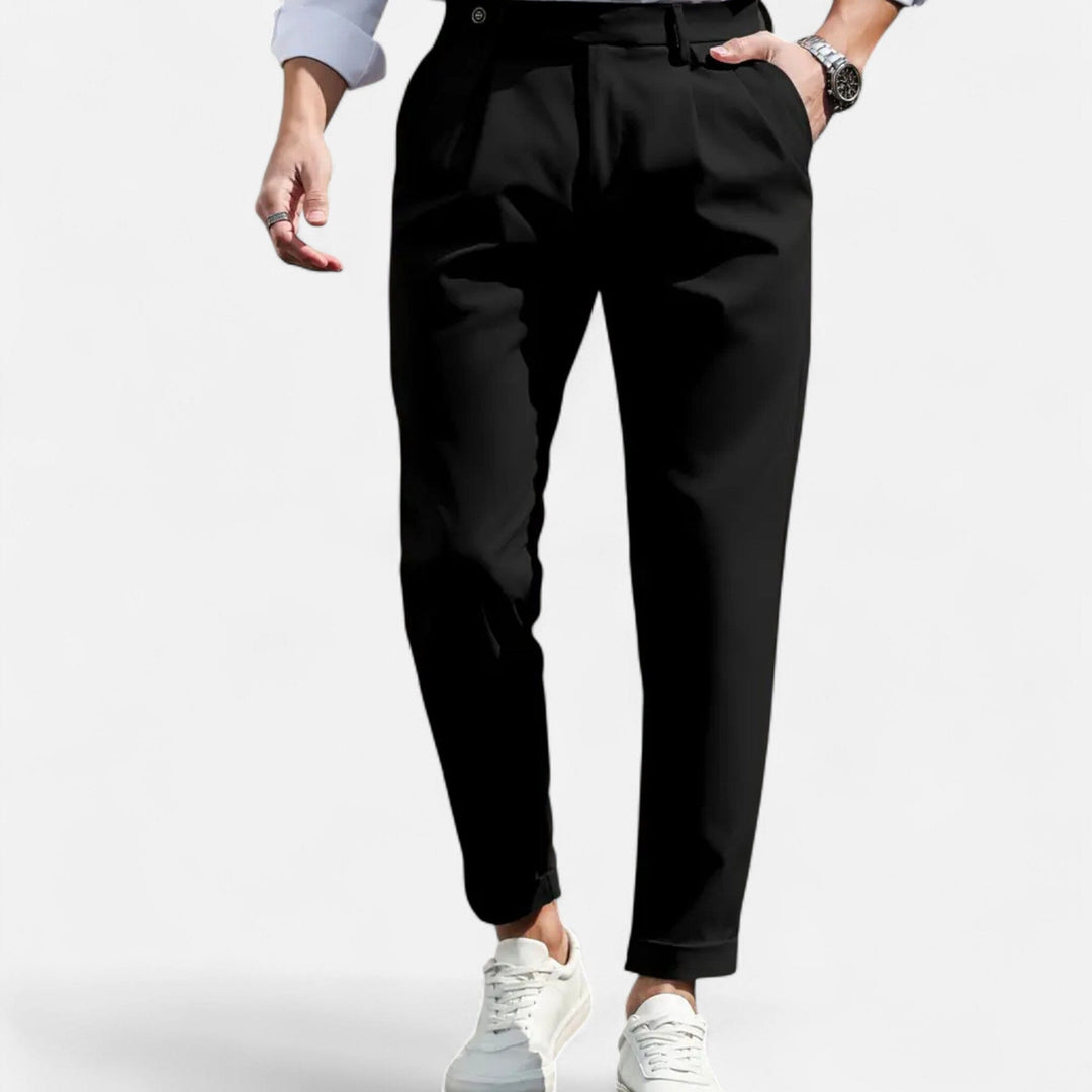  Female model showcasing tailored pleated trousers on a plain background.