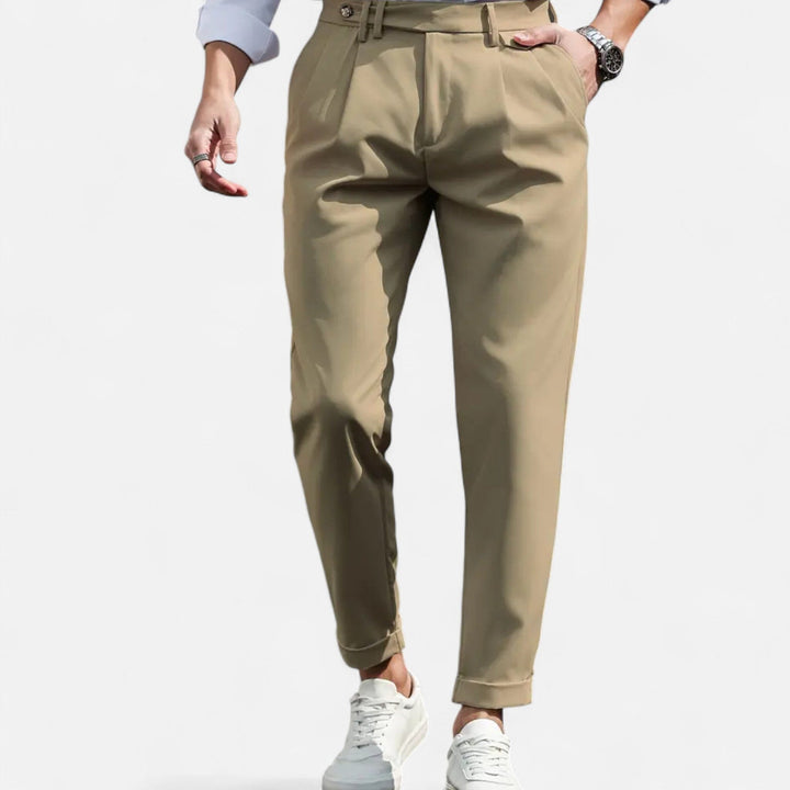 Male model wearing slim fit pleated trousers against a plain background.