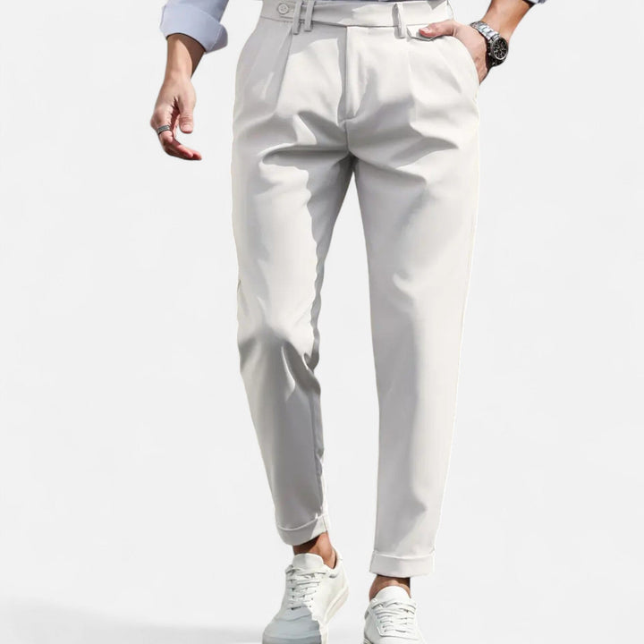  Male model displaying classic pleated dress trousers against a plain background.