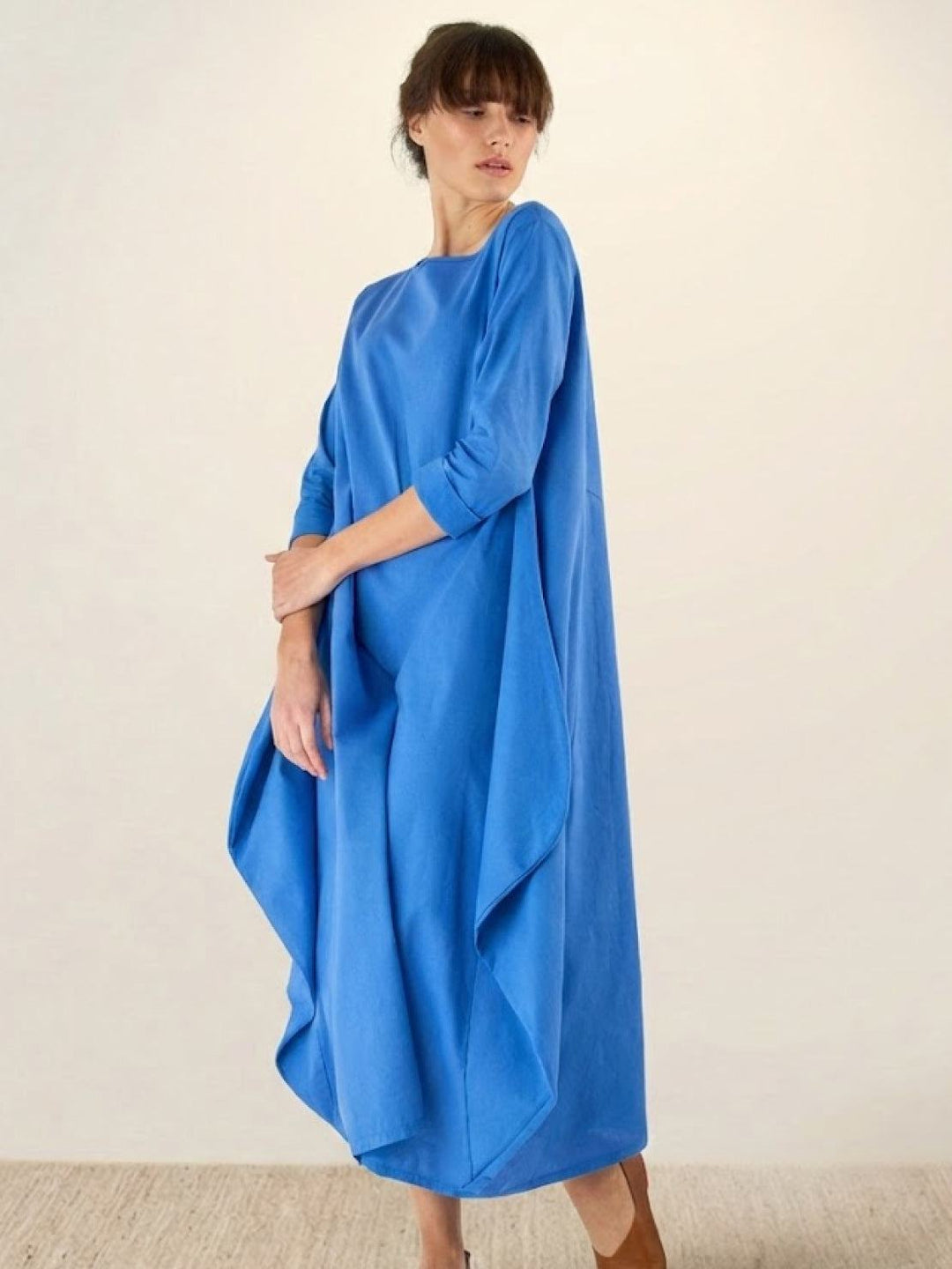 Woman wearing a flowing long dress paired with casual styling.