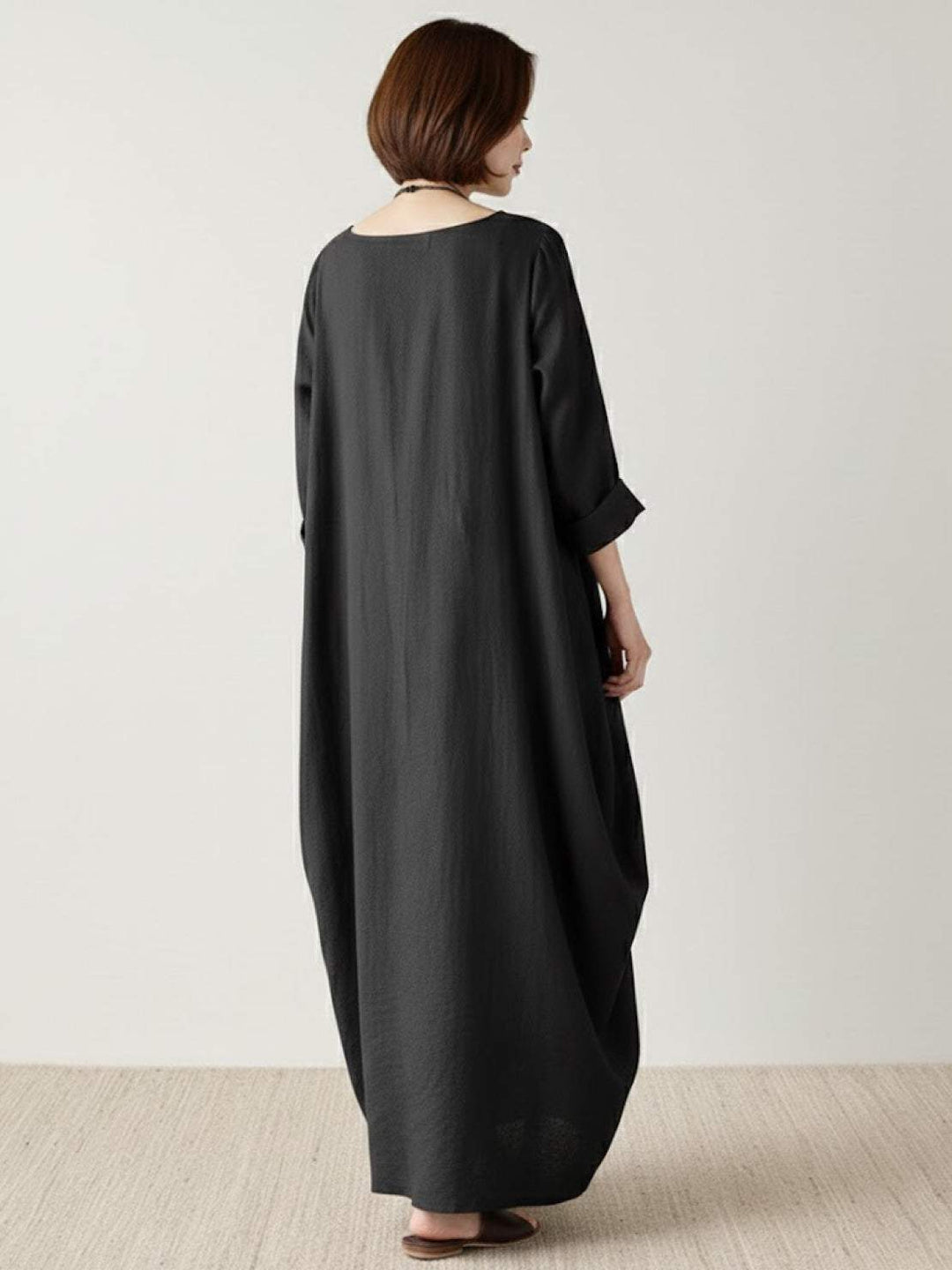 Female model posing in a loose draped dress with clean minimal styling.