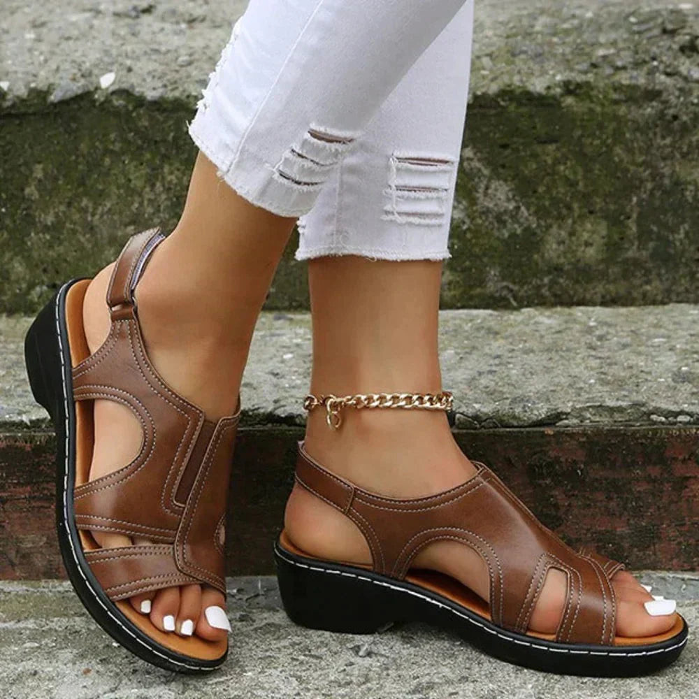 Woman’s foot wearing orthopedic sandal on a plain background.
