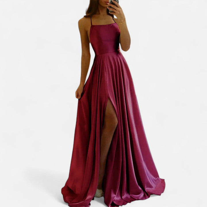 Woman wearing slim strap dress with elegant silhouette, plain background.