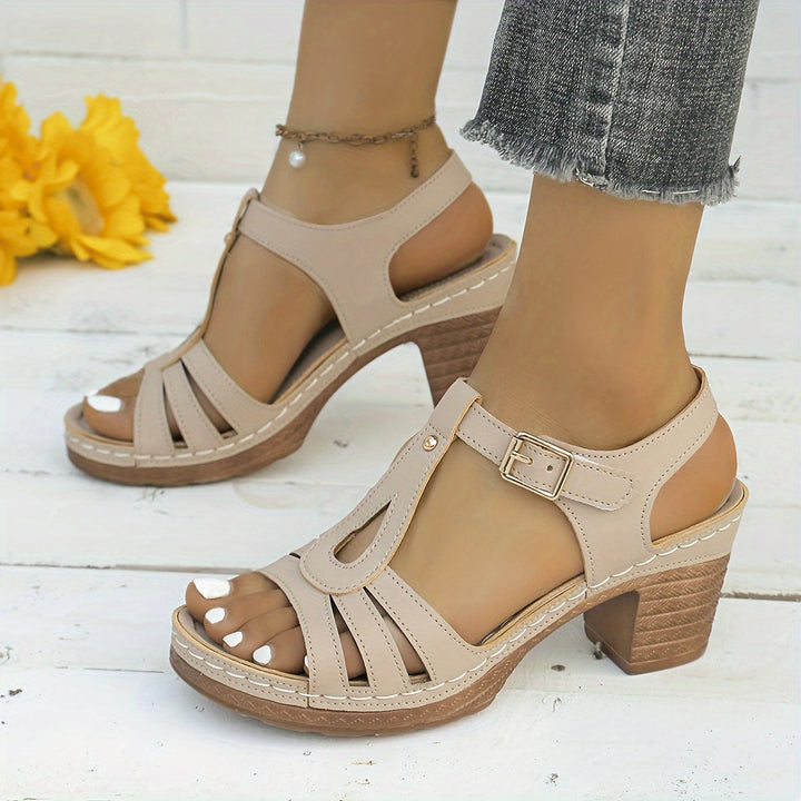 Close-up of feet in open-toe buckle sandals against a plain background.