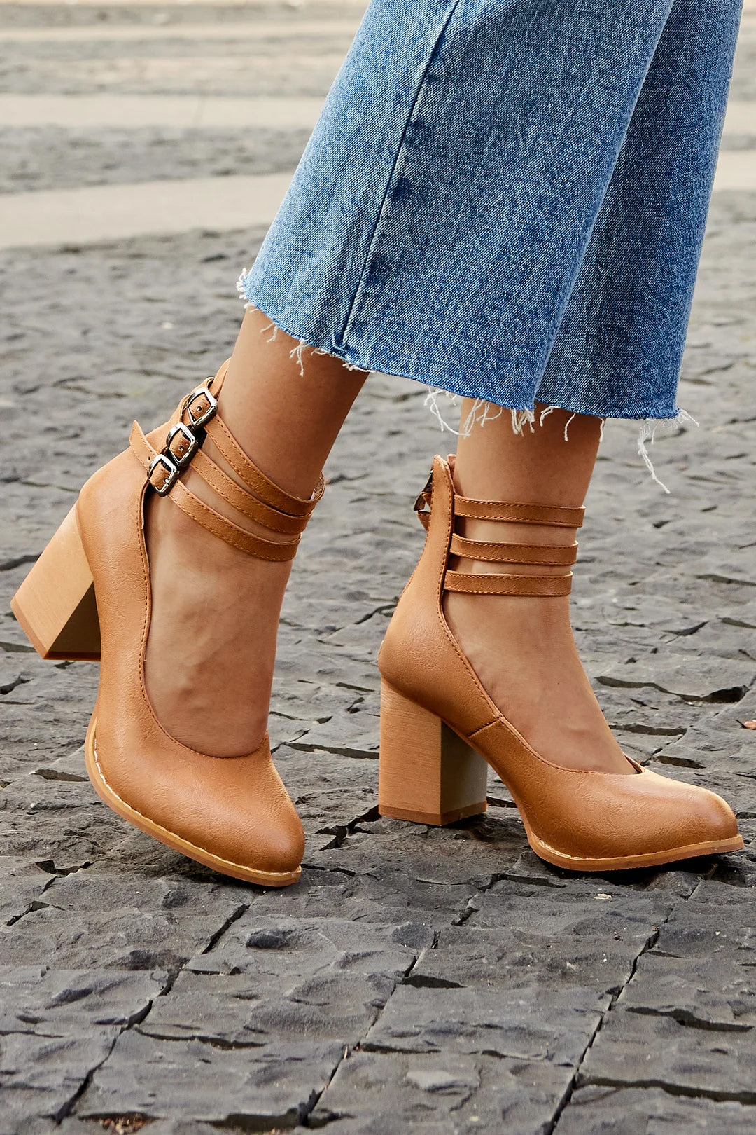 Female model wearing colourful fringe flat shoes on a plain background.