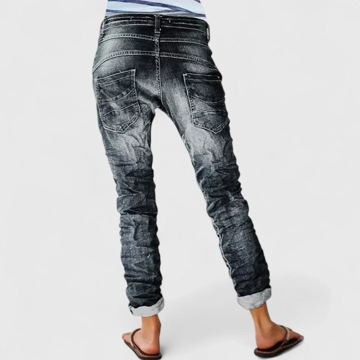 Grey distressed tapered jeans with textured detailing on a plain background, back view