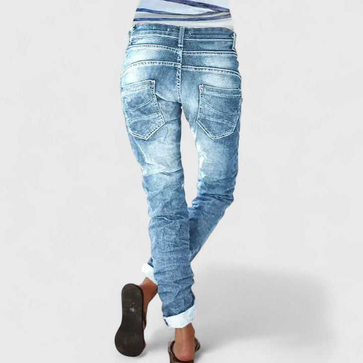 Mid-rise tapered jeans with distressed finish on a plain background.