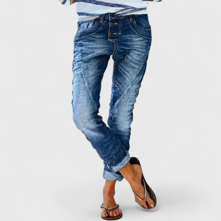 Woman's jeans with tapered leg and textured distressing on a plain background.