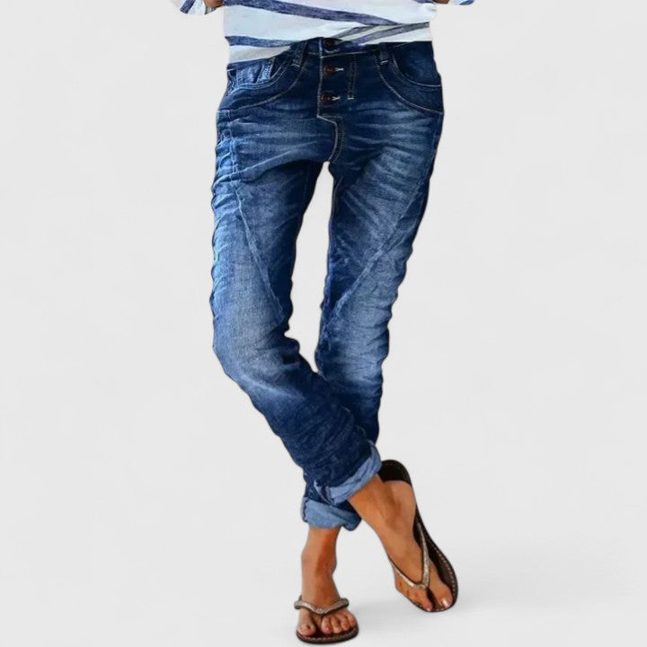 Tapered denim jeans with worn details on a plain background.