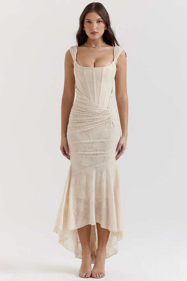 Female model wearing a fitted evening dress with gathered fabric detail against a plain background.