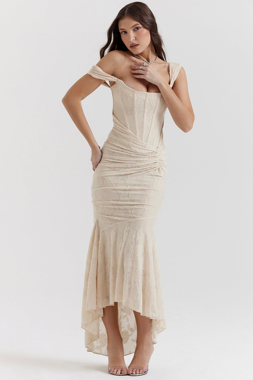Woman posing in a ruched sleeveless dress for formal night styling on a clean background.