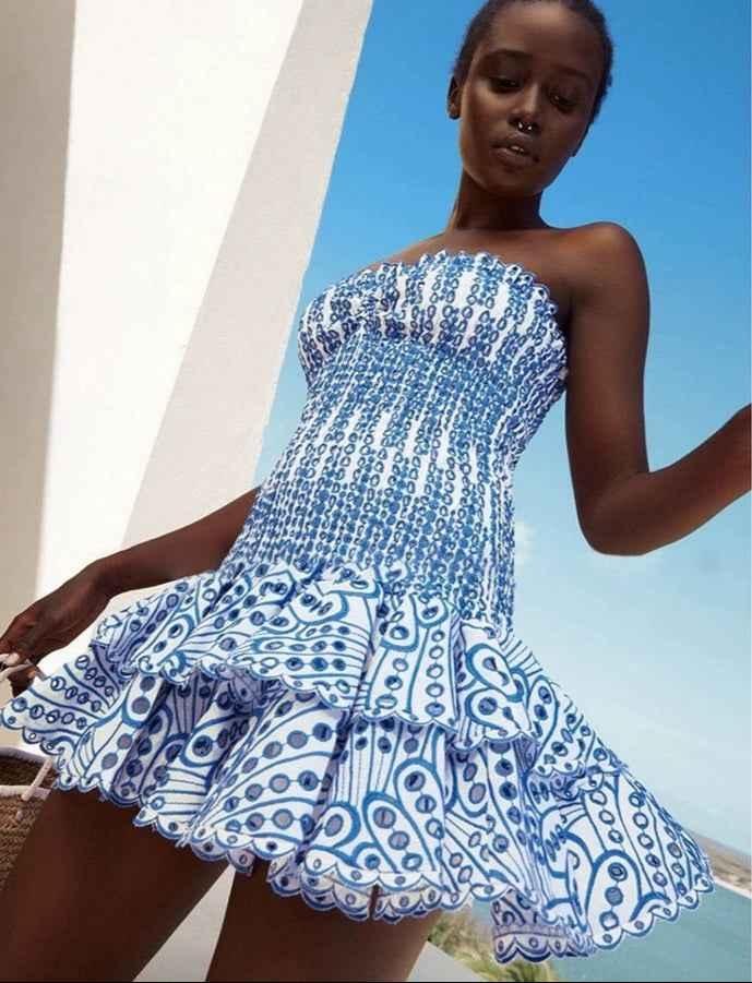  Female model posing in a lightweight off-shoulder dress with layered ruffle details against a plain background.