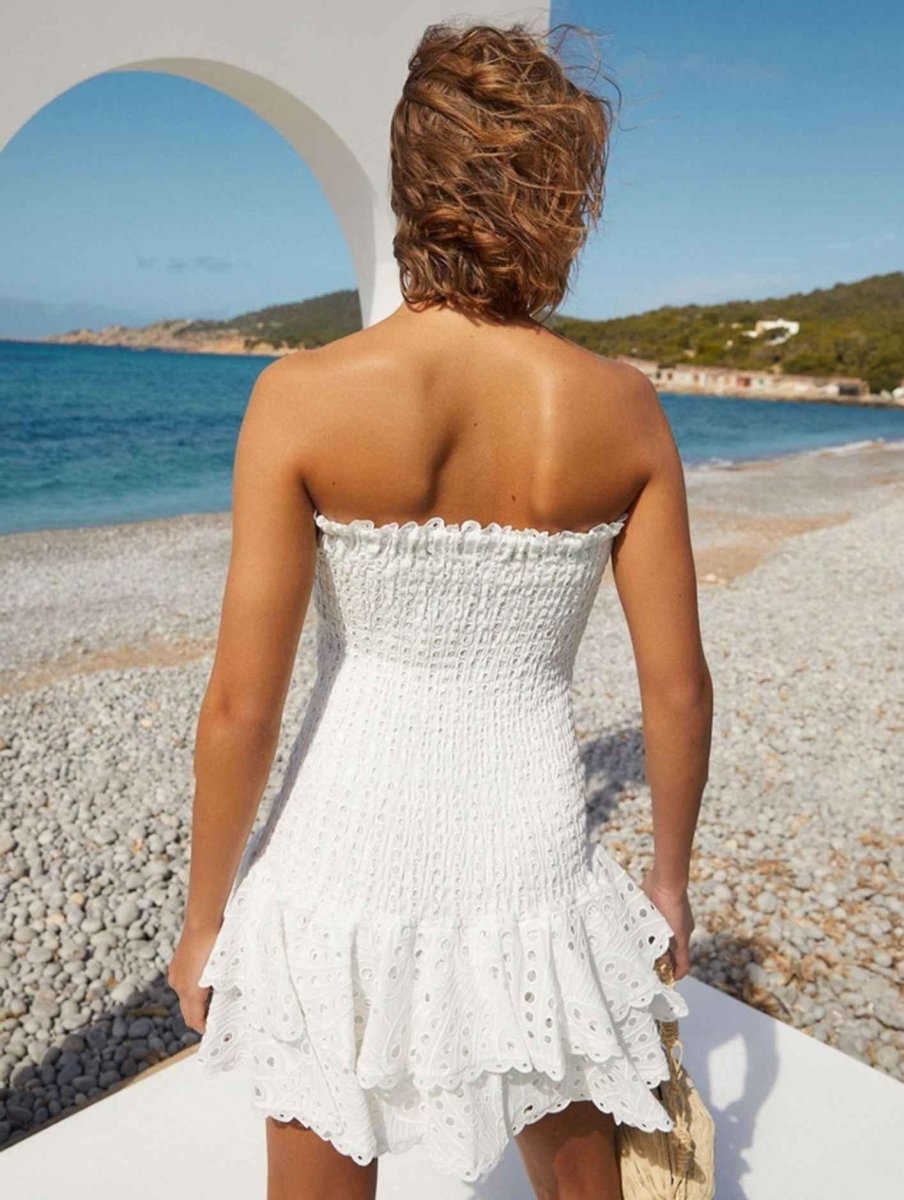  Female model displaying a flowy tiered dress with soft detailing against a plain background.