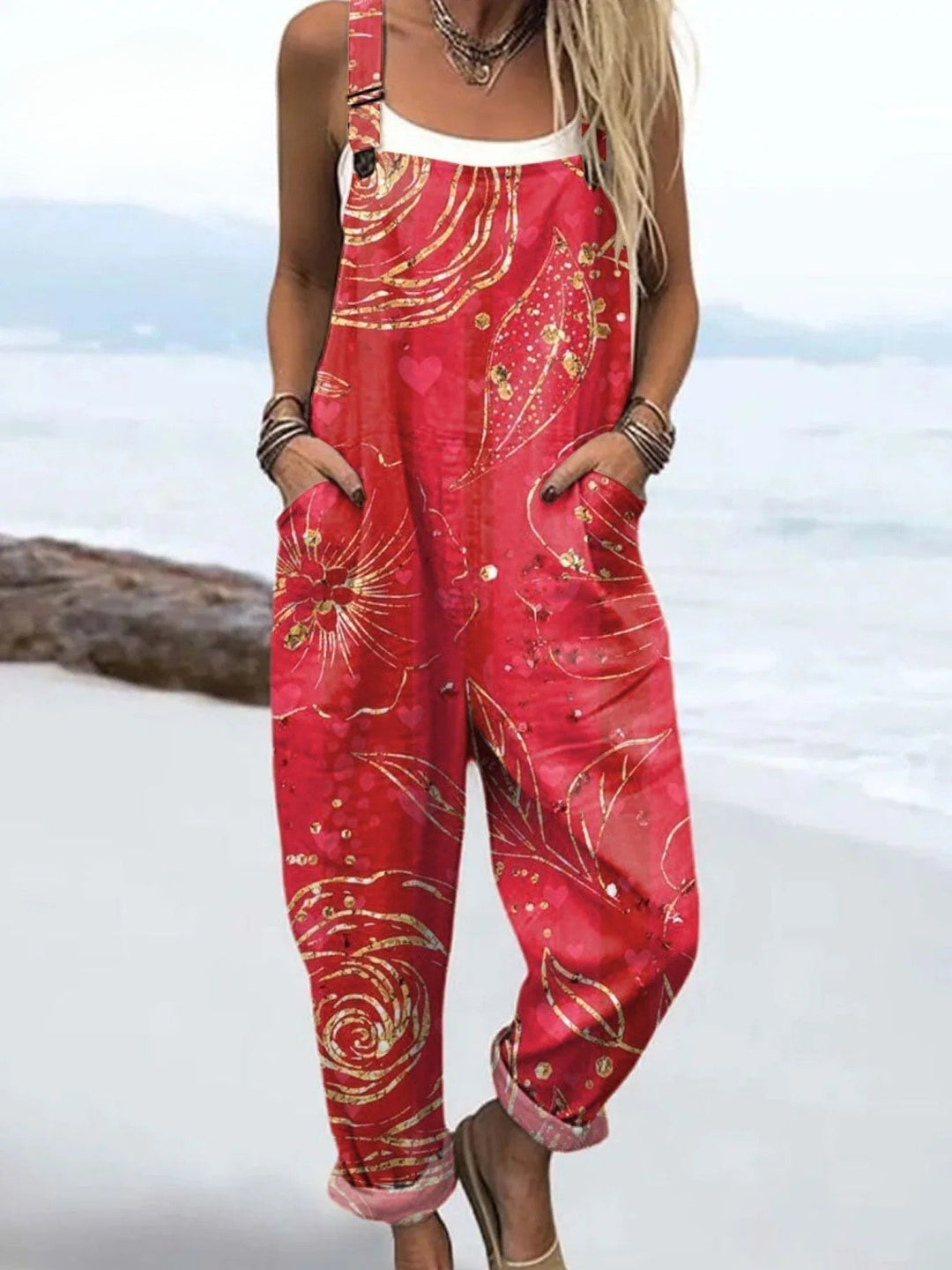 Woman in a breezy floral jumpsuit shown on a plain background.