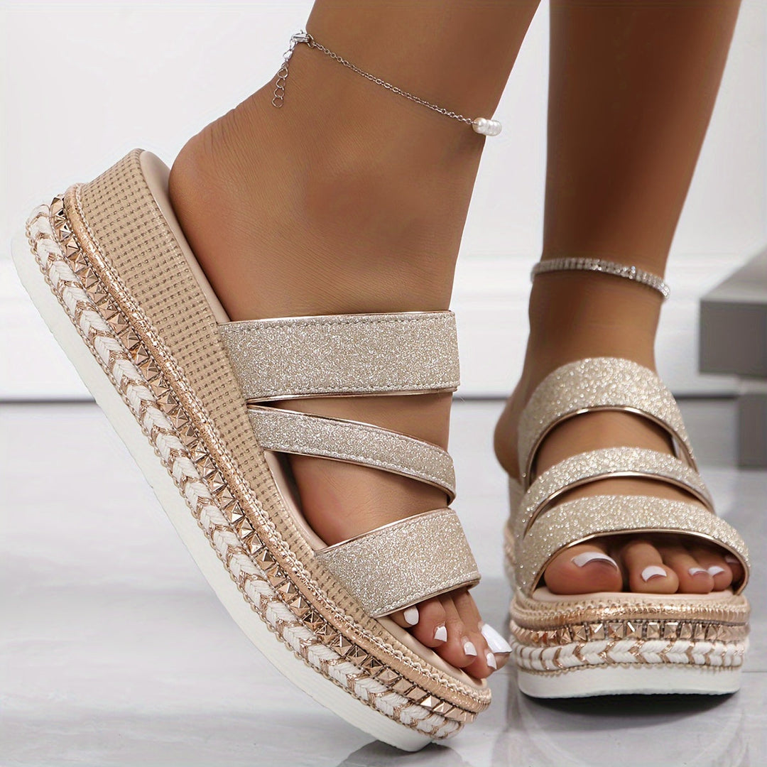 Woman feet in lightweight champagne sandals on a clean background.