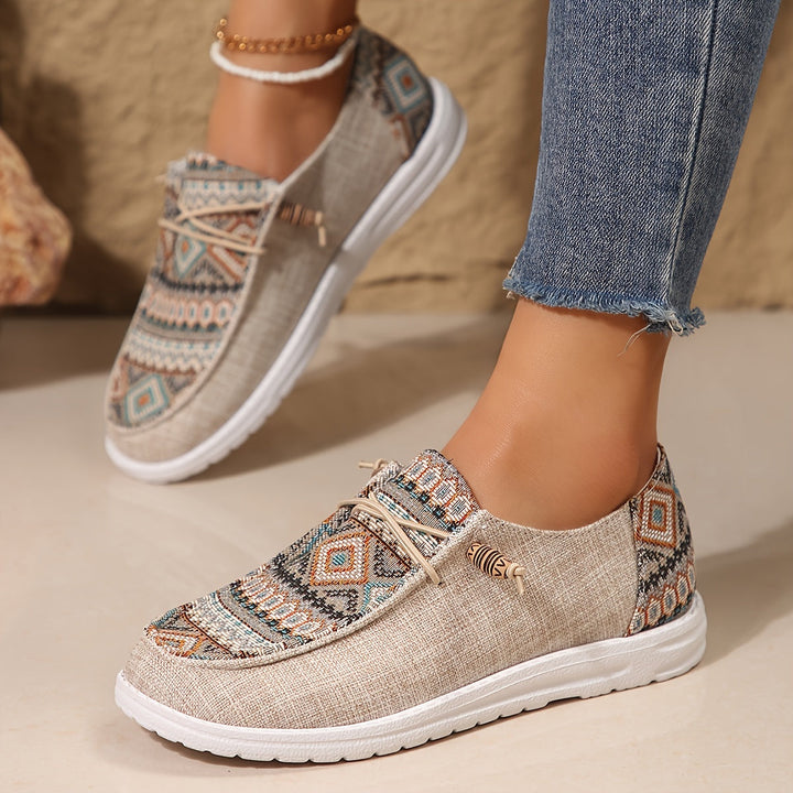 Feet wearing artistic print sneakers displayed on a plain background.