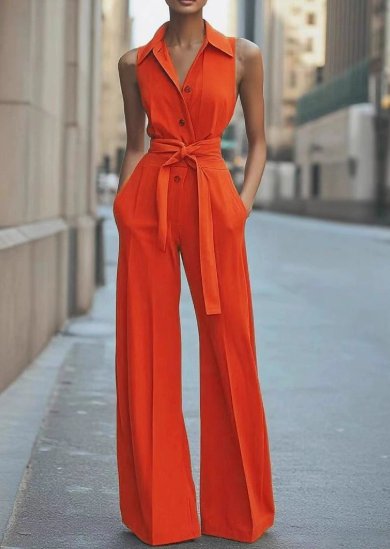 Female model wearing a sleeveless wide leg jumpsuit with a tie waist on a plain background.