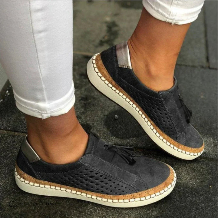Close-up of feet wearing casual slip-on sneakers on a plain background.