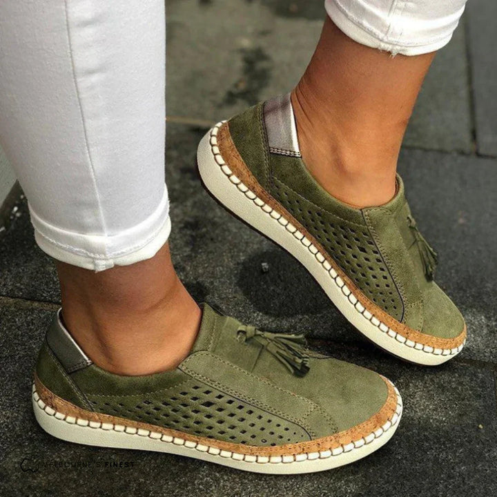 Woman wearing slip-on sneakers on a plain background with feet shown.