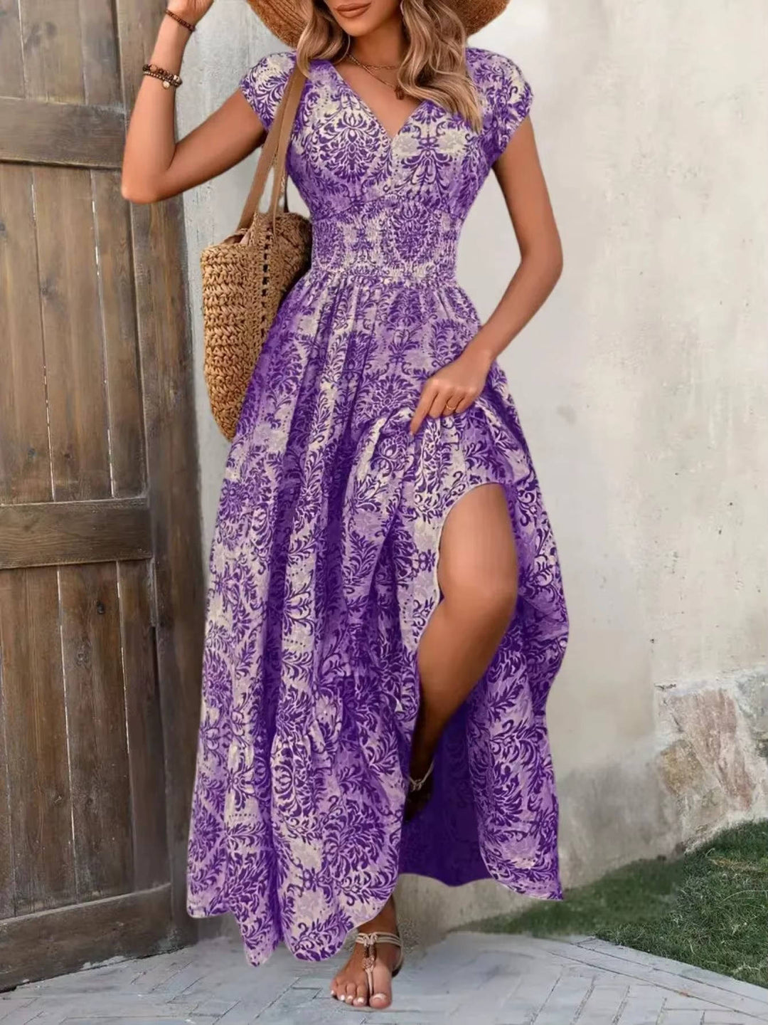 Female model posing in a flowy summer maxi dress on a plain backdrop