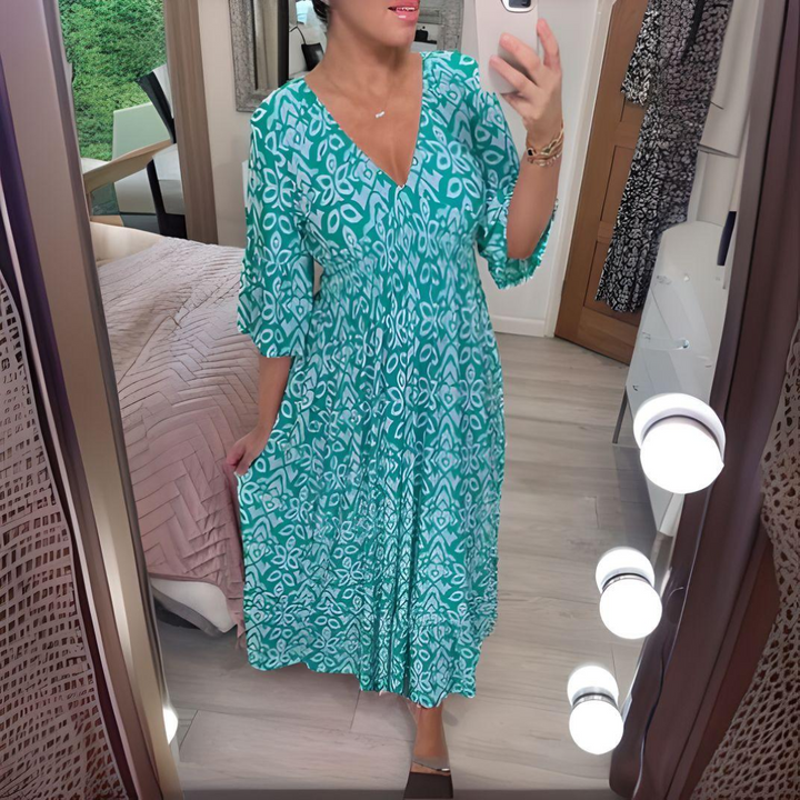 Woman styled in a casual printed dress with short sleeves on a bedroom background.