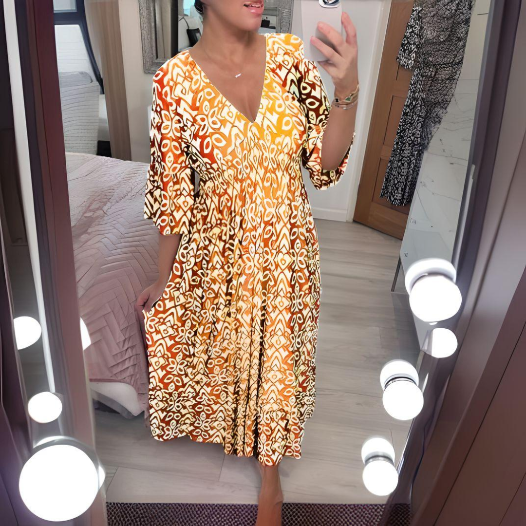 Woman in a round neck printed dress shown on a bedroom background.