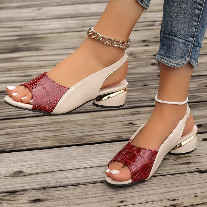 Close-up of foot in chic open-toe sandal on a plain background.