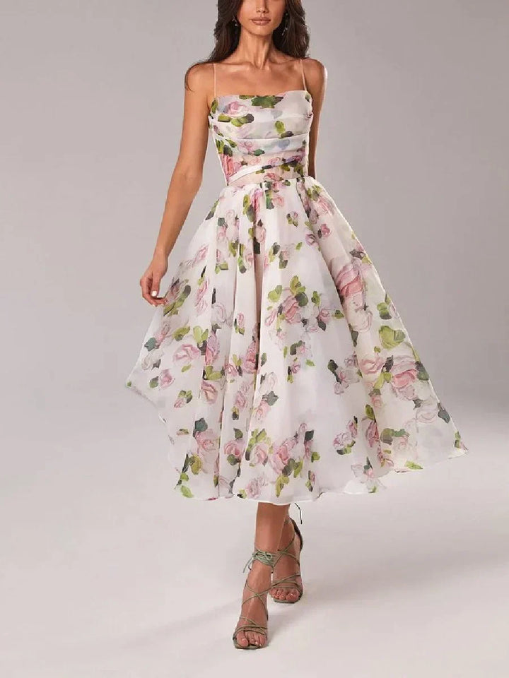 Female model wearing a floral print strapless midi dress with a fitted bodice and flowing full skirt against a plain background.