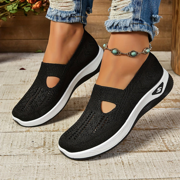 Close-up of feet wearing modern slip-on shoes against a plain backdrop.